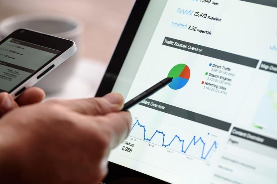 a man pointing at a graph on his laptop with a pen