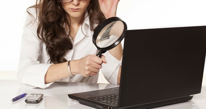 a woman using magnifying glass on her laptop