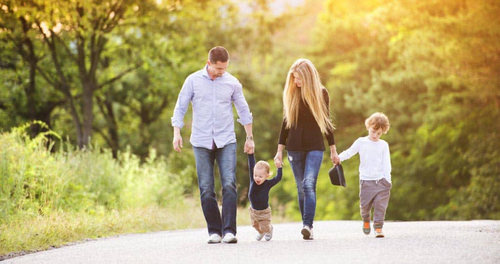 A family consists of mother, father with 2 kids having a walk in the park